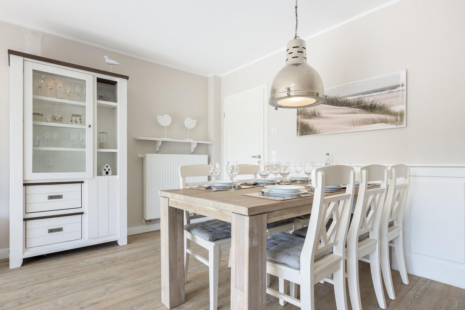Dining room with table, chairs, and glass cabinet. Wall picture shows beach.