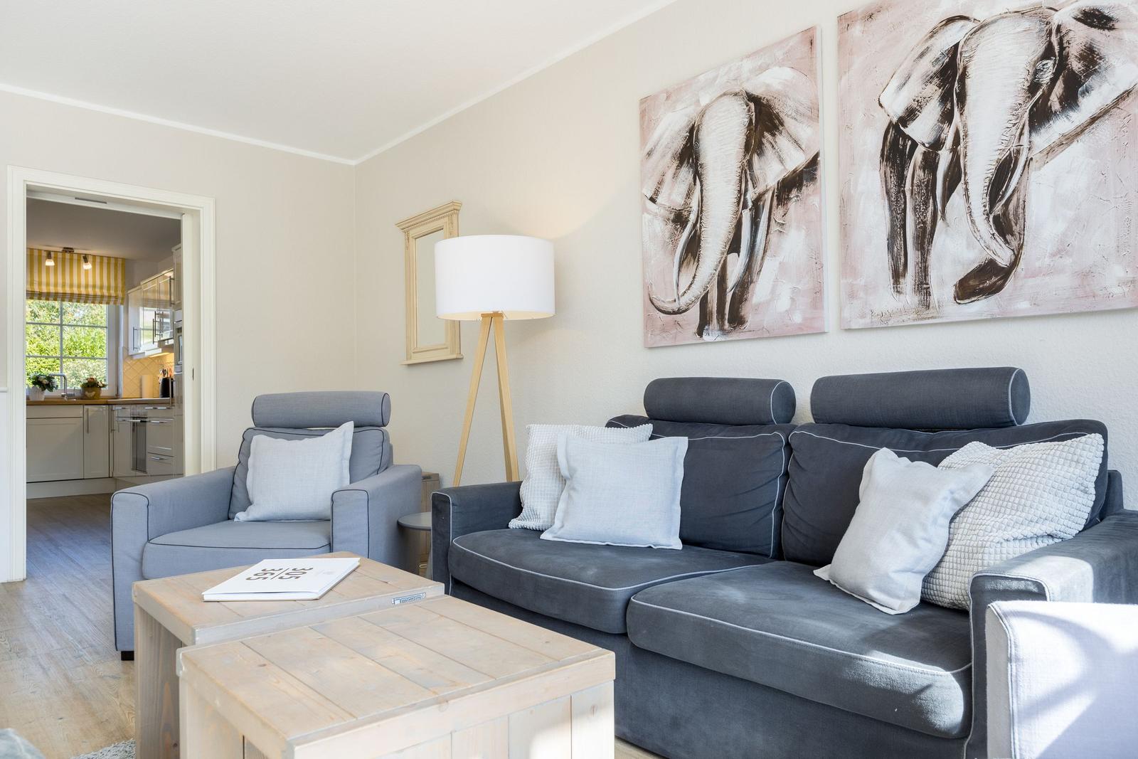 Living room with sofa, armchair, and wall art of elephants.