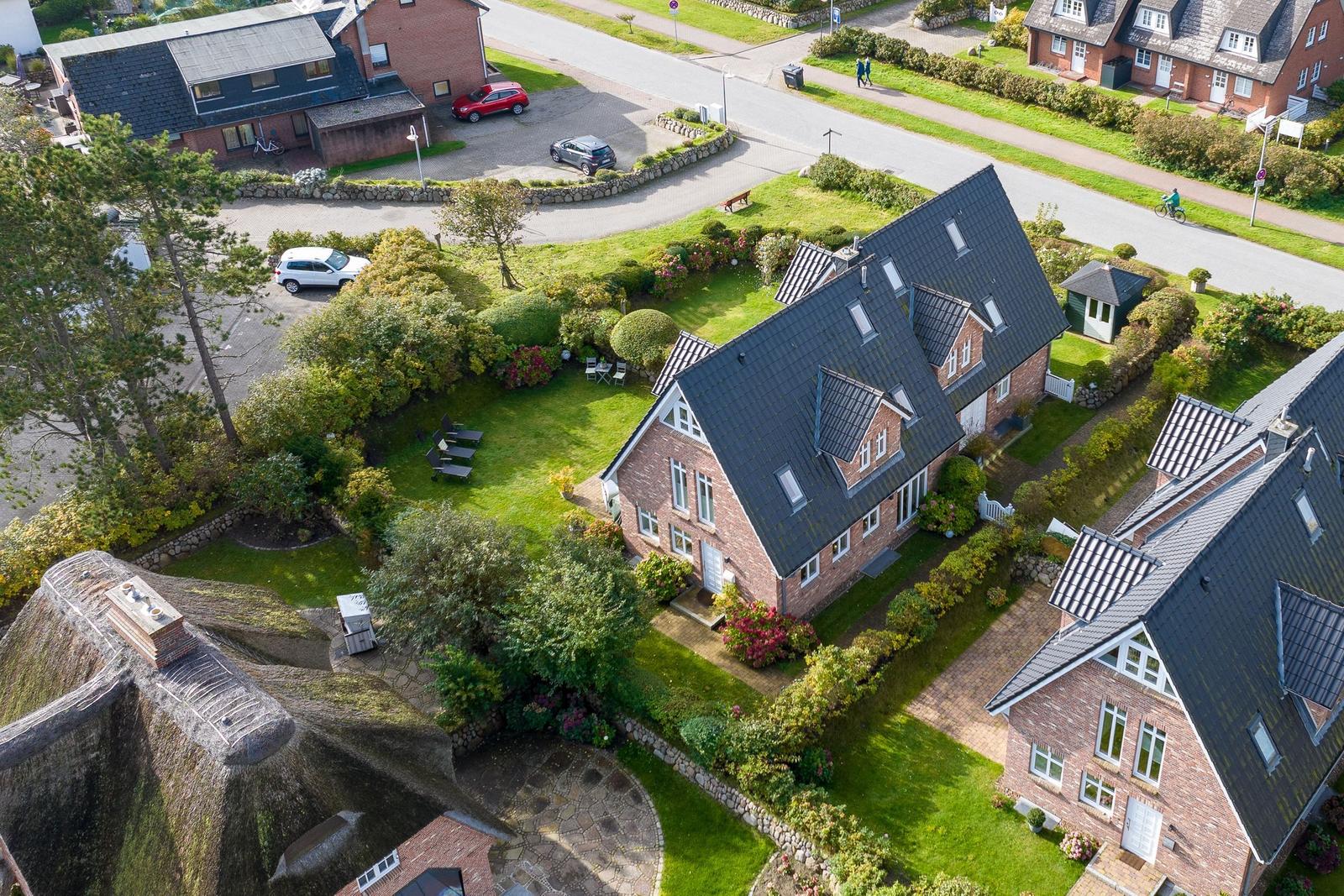 House with garden, terrace, and parking. Surroundings with trees and road.