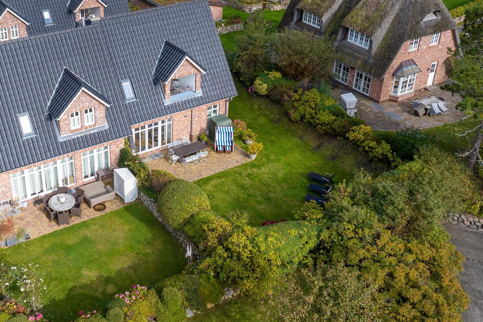 House with garden, terrace, and garden furniture. Adjacent house with thatched roof.