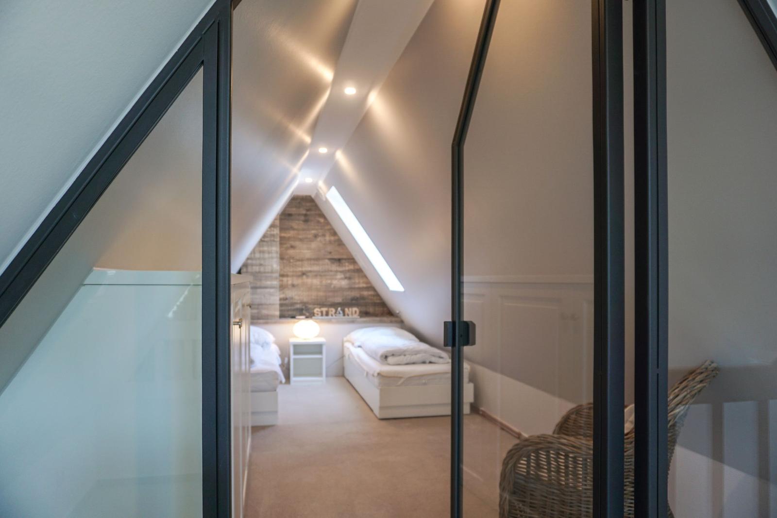Room with two beds, sloped ceiling, and glass wall