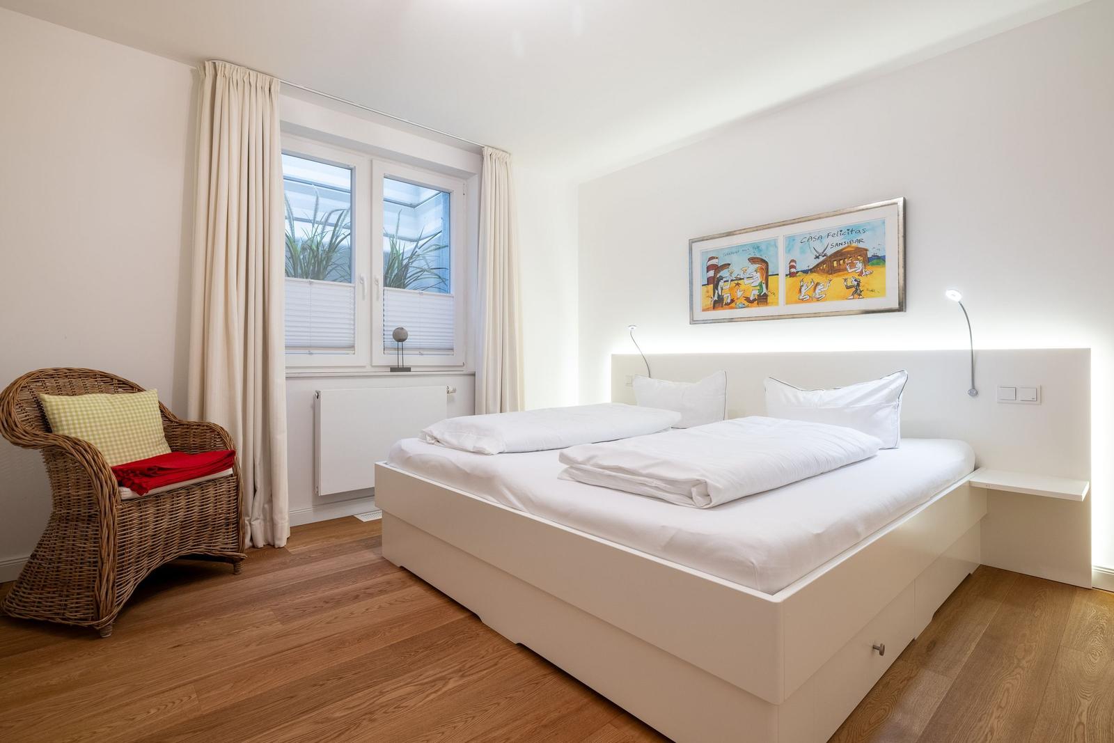 Bedroom with double bed, wicker chair, and window view.