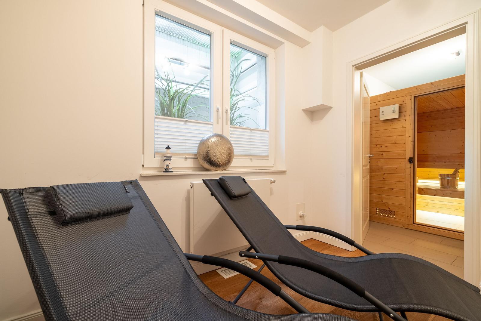 Two lounge chairs by window, sauna in background