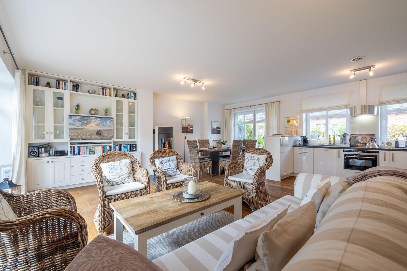 Living room with sofa, chairs, and dining table. Kitchen and TV area are visible.