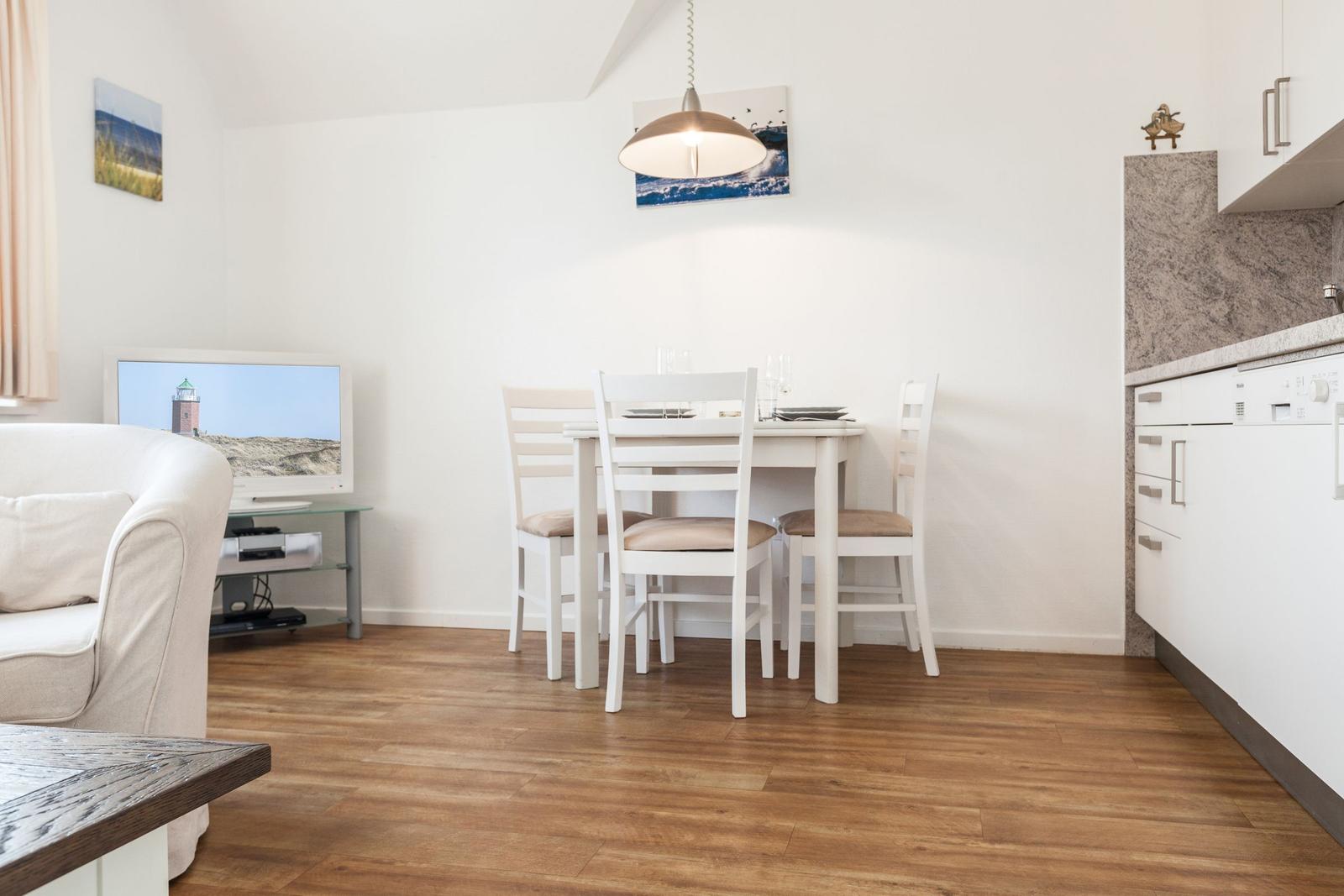Wohnzimmer mit Essbereich, Fernseher und Küchenzeile.