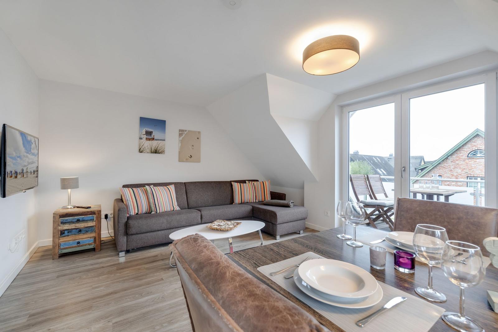 Living and dining area with sofa, table, and balcony view.