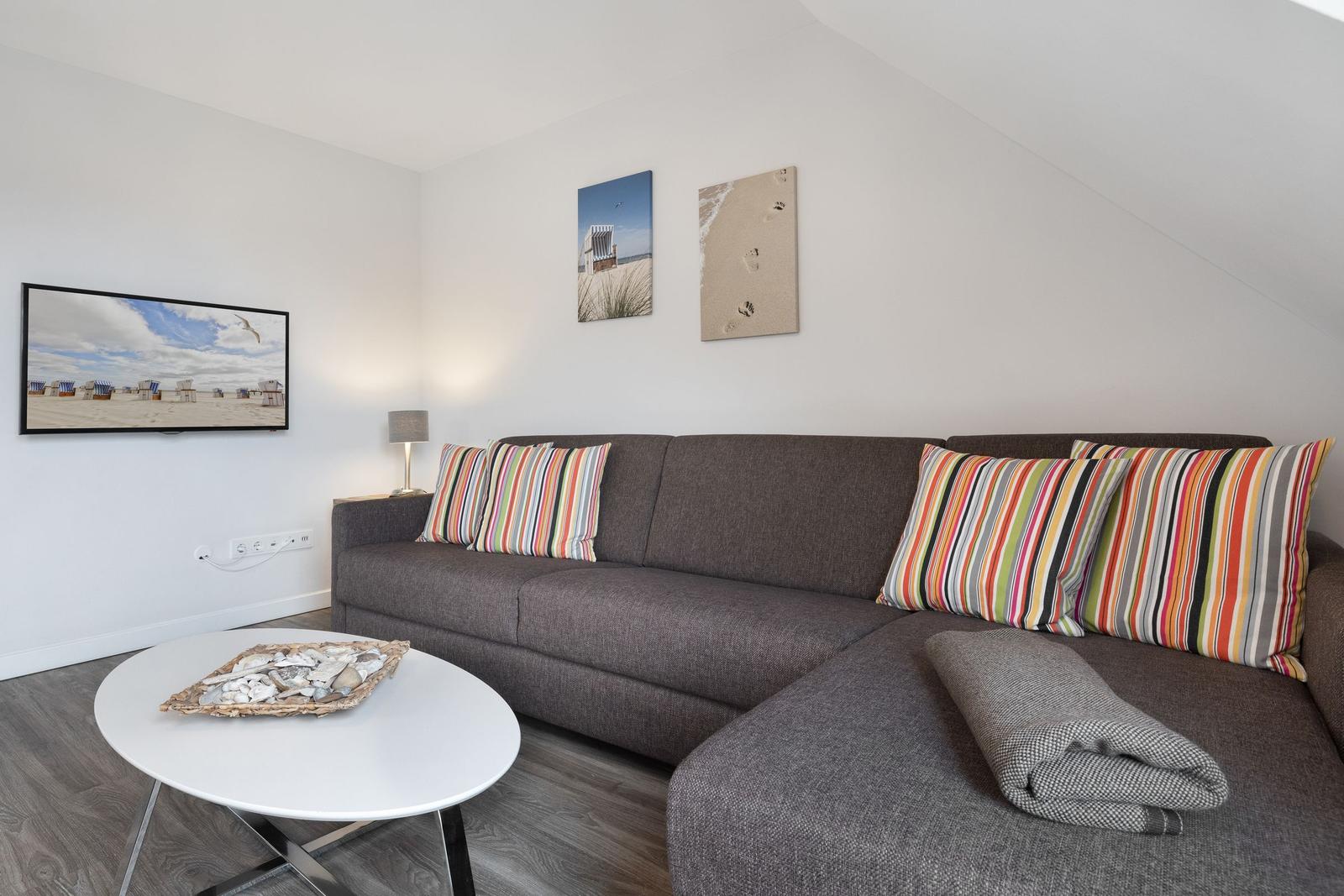 A living room with a gray sofa, colorful cushions, and a round table.