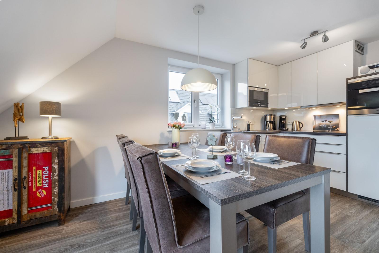 Dining room with table, chairs, and kitchen. Attic with window and lamp.
