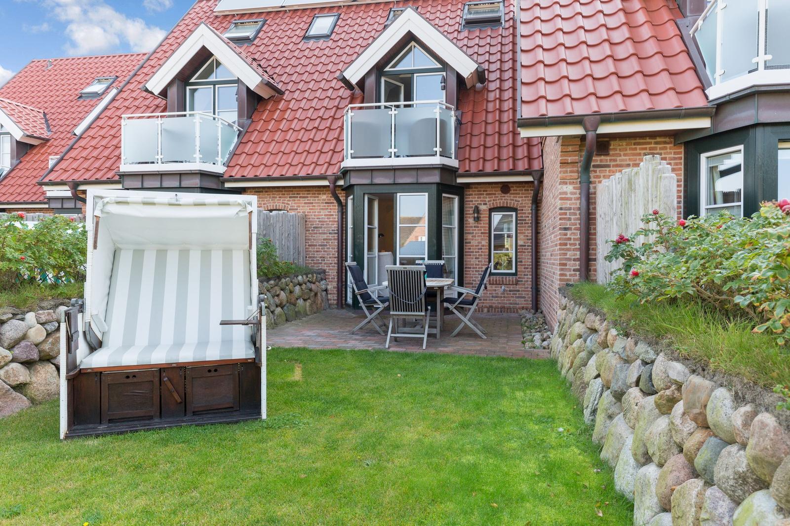 House with terrace, garden, and beach chair. Red tiled roof and stone wall.