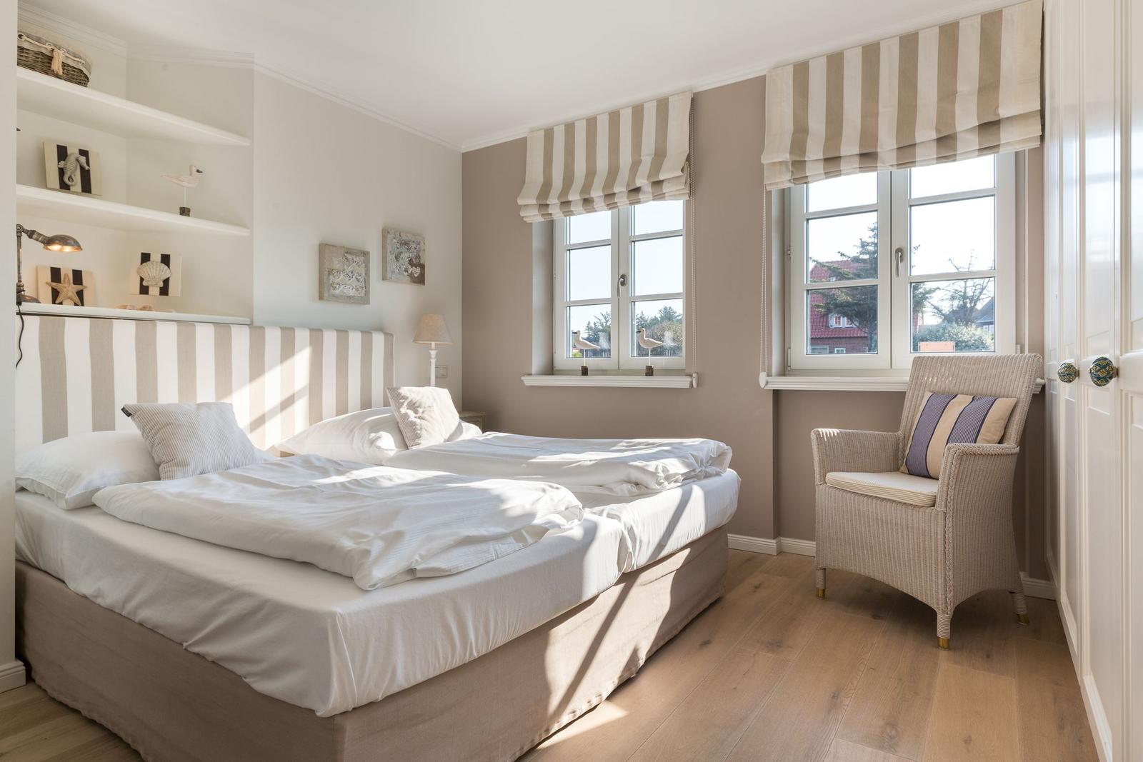 Bedroom with double bed, two windows, and chair.