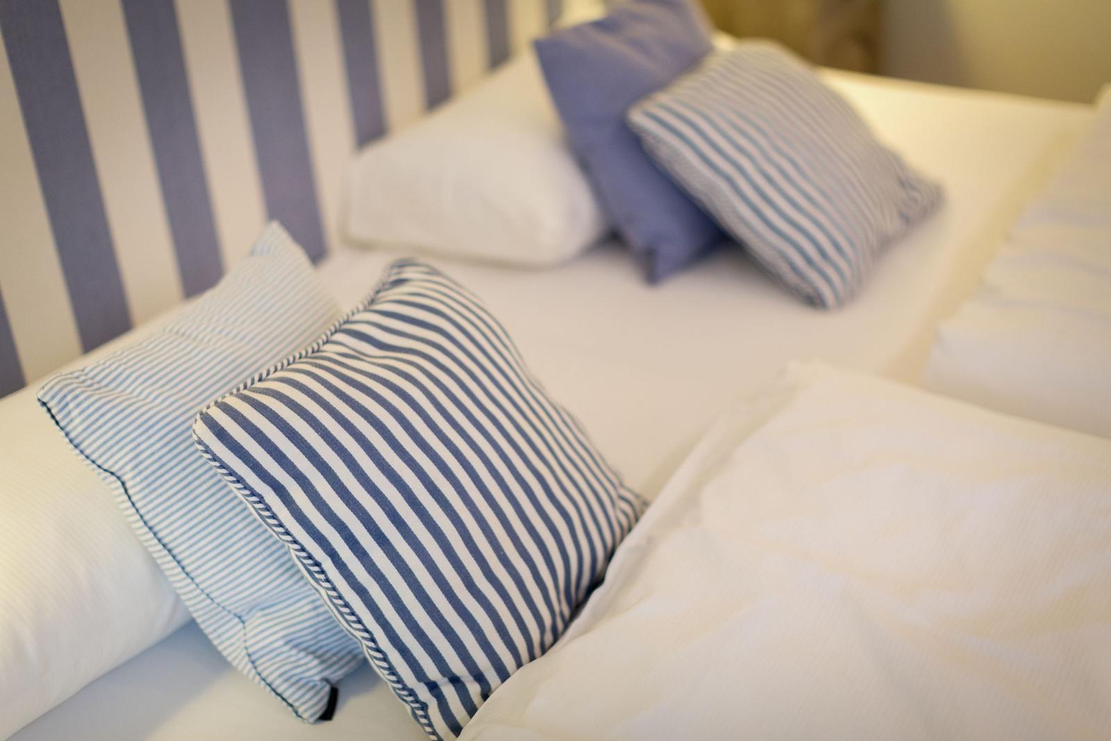 Double bed with pillows and striped headboard.