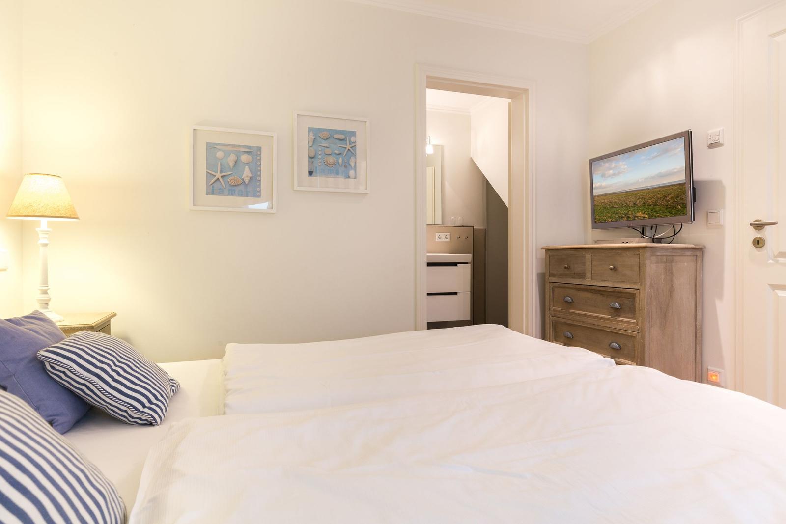 Bedroom with bed, TV, and pictures on the wall.