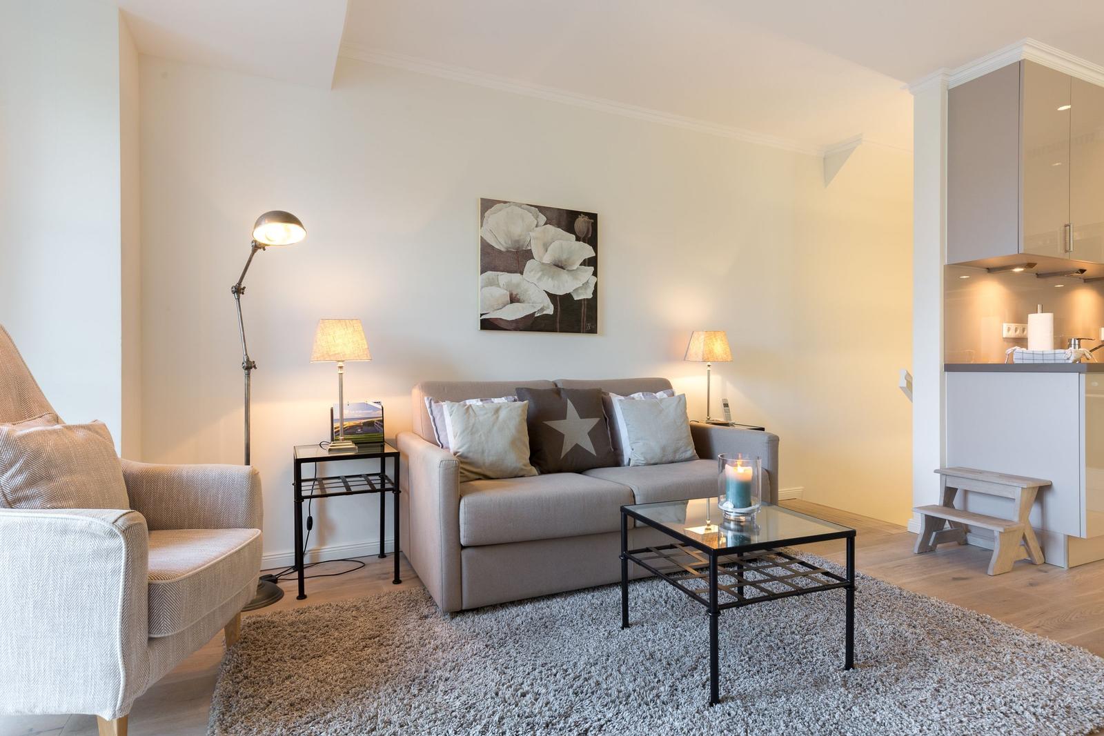 Living room with sofa, armchair, table, and wall art.