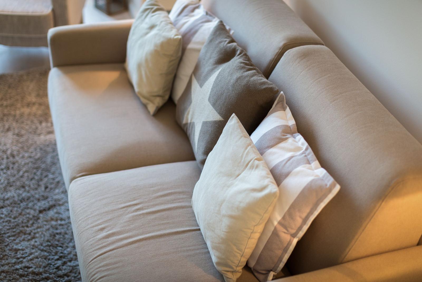 A sofa with multiple cushions on a rug