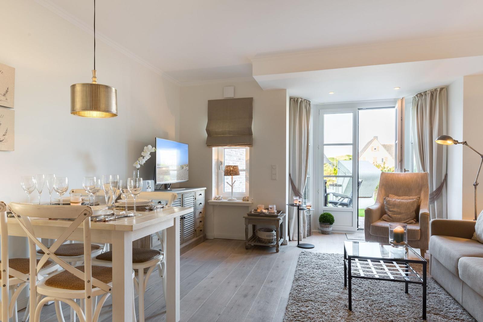 Dining area with table and chairs, living area with sofa and armchair, window to terrace.