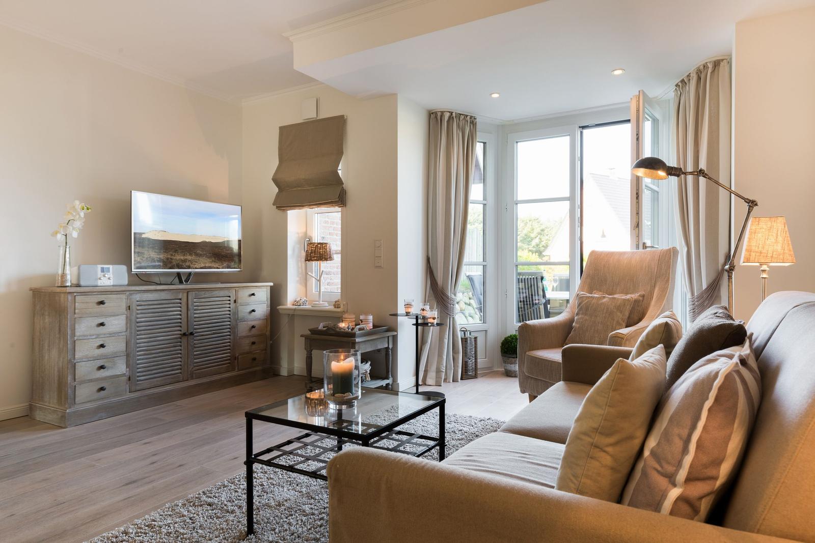 Living room with sofa, armchair, TV, and window to terrace.