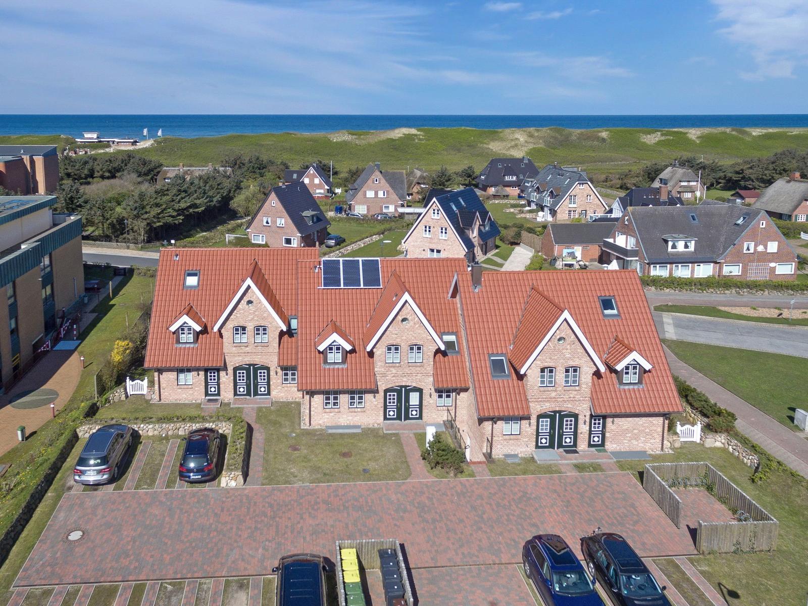 Haus mit rotem Dach und Solaranlage, Blick auf Meer und Grünflächen.