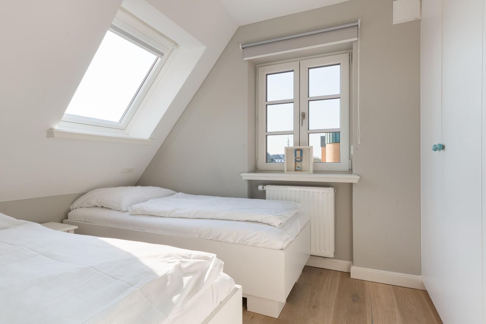 Zimmer mit zwei Betten, Dachfenster und Fenster mit Blick.