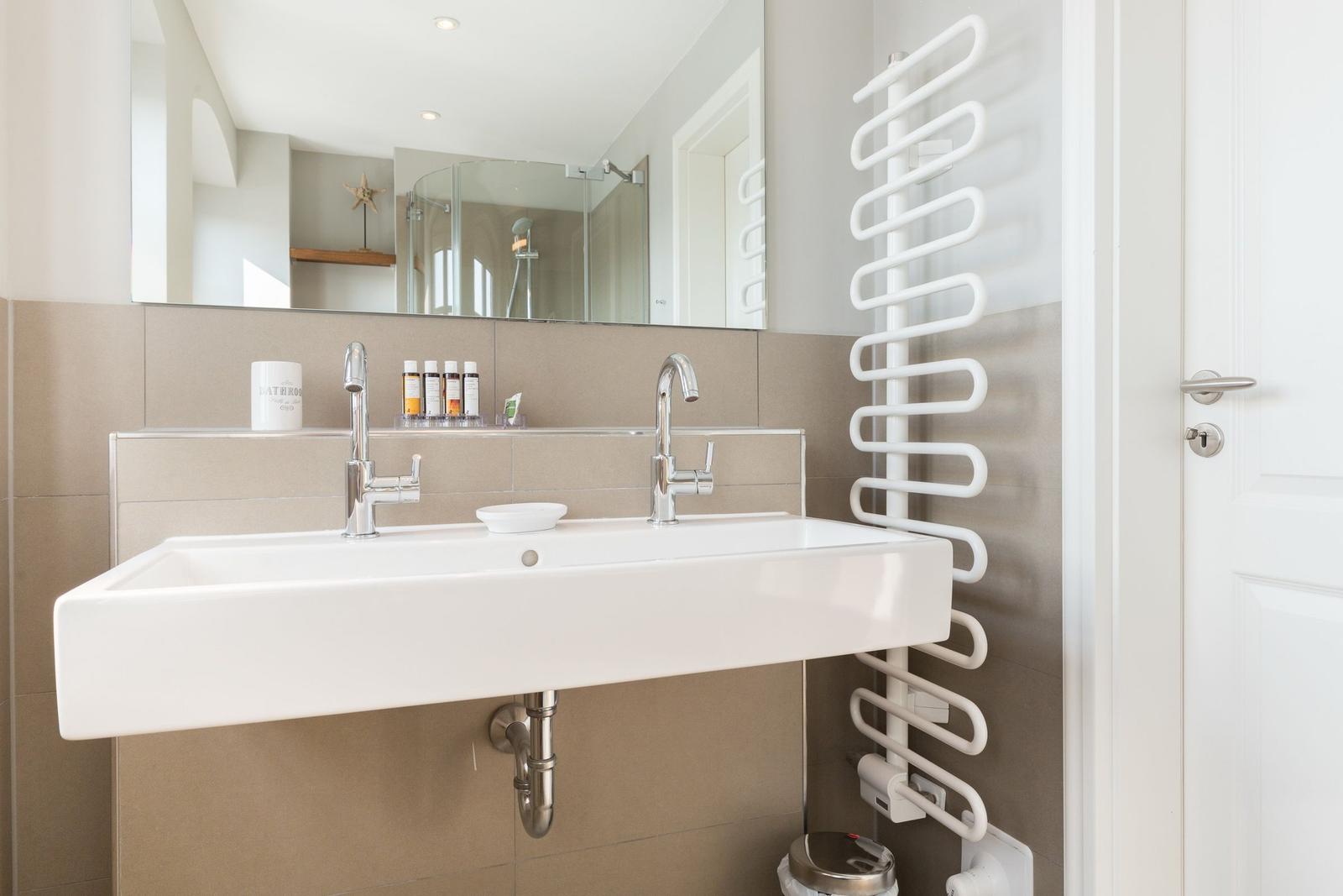 Waschbecken mit Spiegel und Handtuchwärmer an der Wand