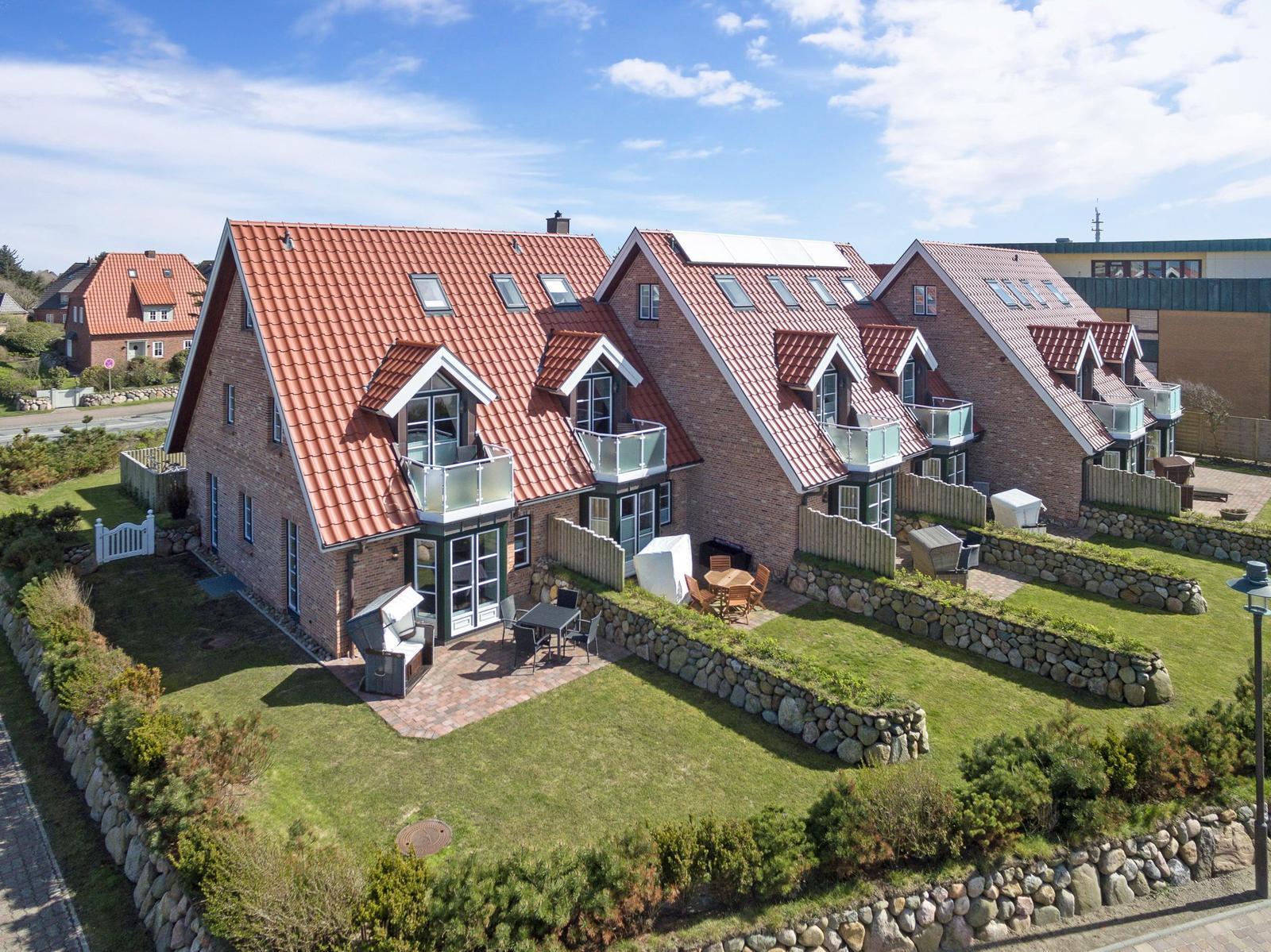 Modernes Mehrfamilienhaus mit Terrassen und Gartenbereich.