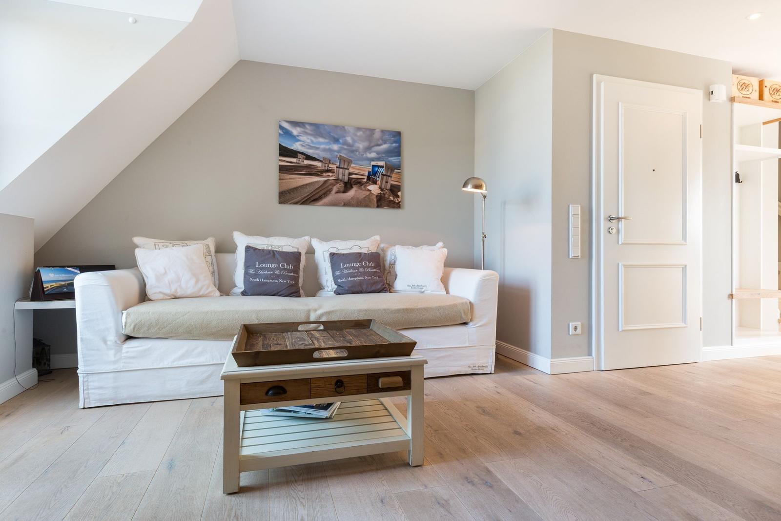 Wohnzimmer mit Sofa, Couchtisch und Wandbild unter Dachschrägen.
