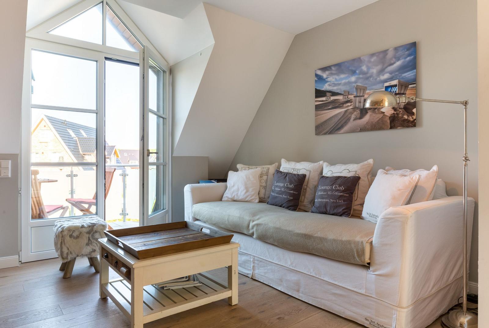 Wohnzimmer mit Sofa, Couchtisch und Blick auf Balkon