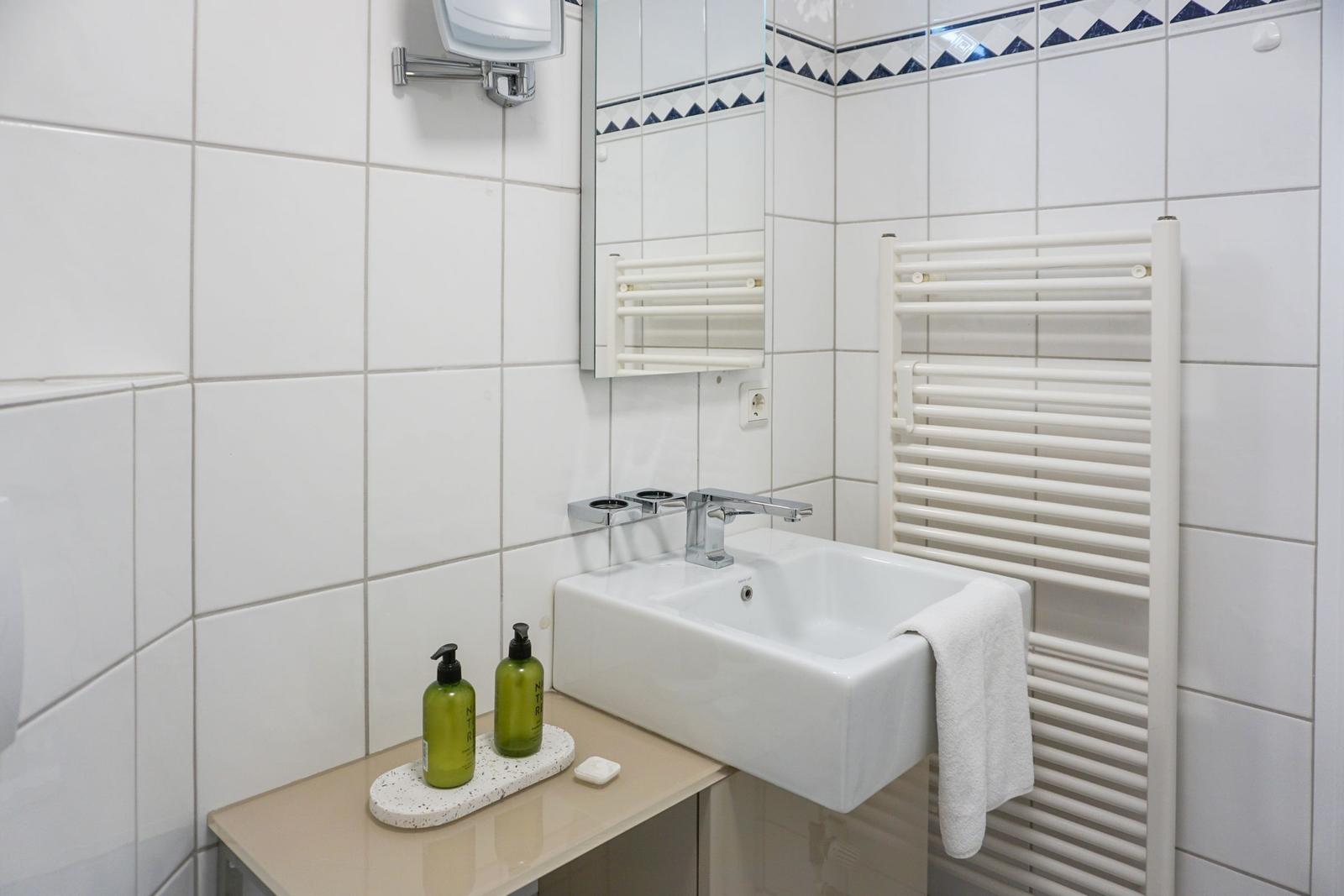 Bathroom with sink, mirror, and towel heater.