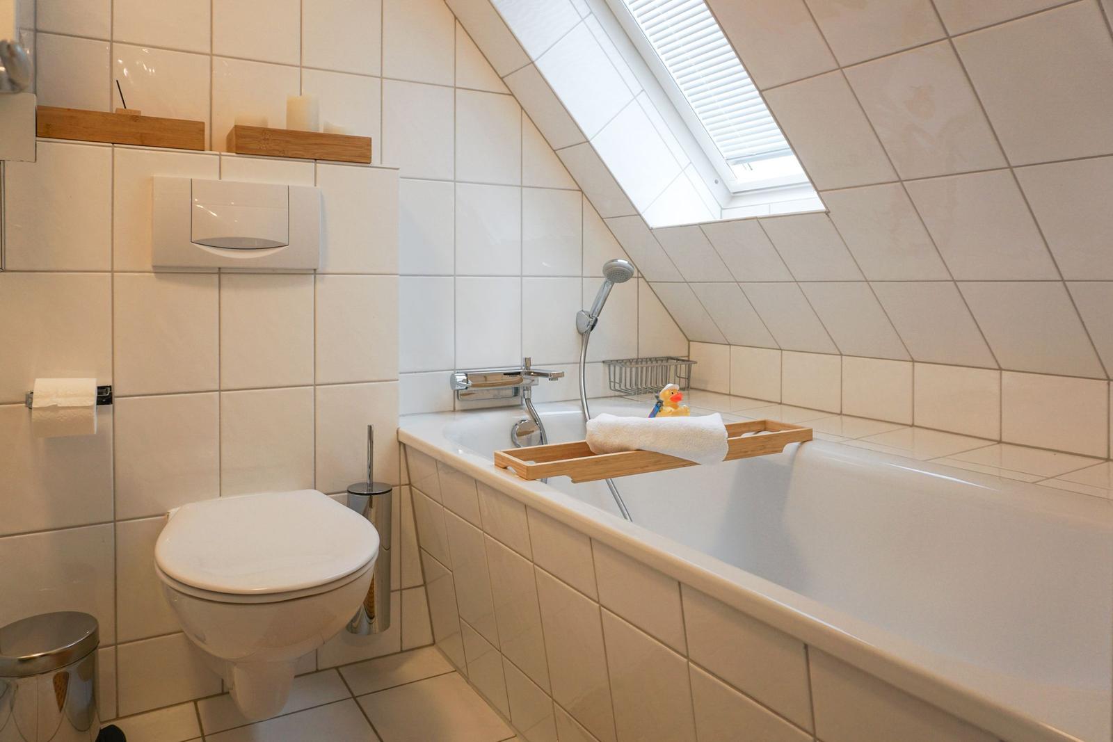 Bathroom with bathtub, shower, and toilet under sloped ceilings