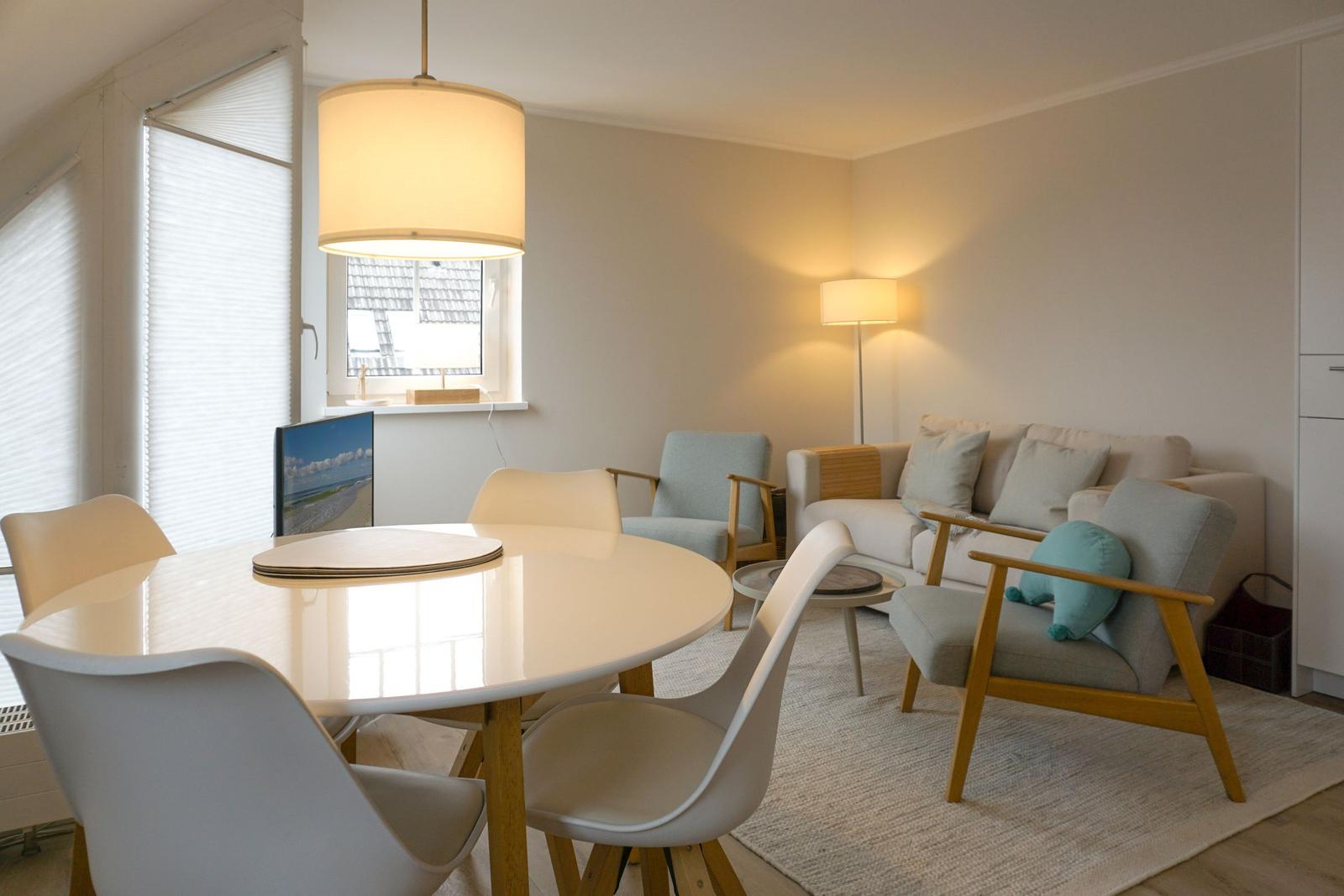 Dining area with round table and chairs. Living area with sofa and armchairs.