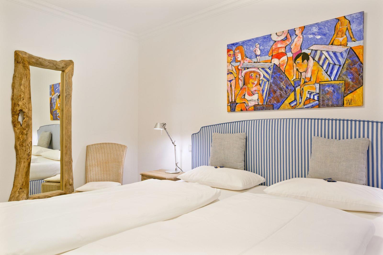 Schlafzimmer mit Bett, Wandbild und Spiegel mit rustikalem Rahmen.
