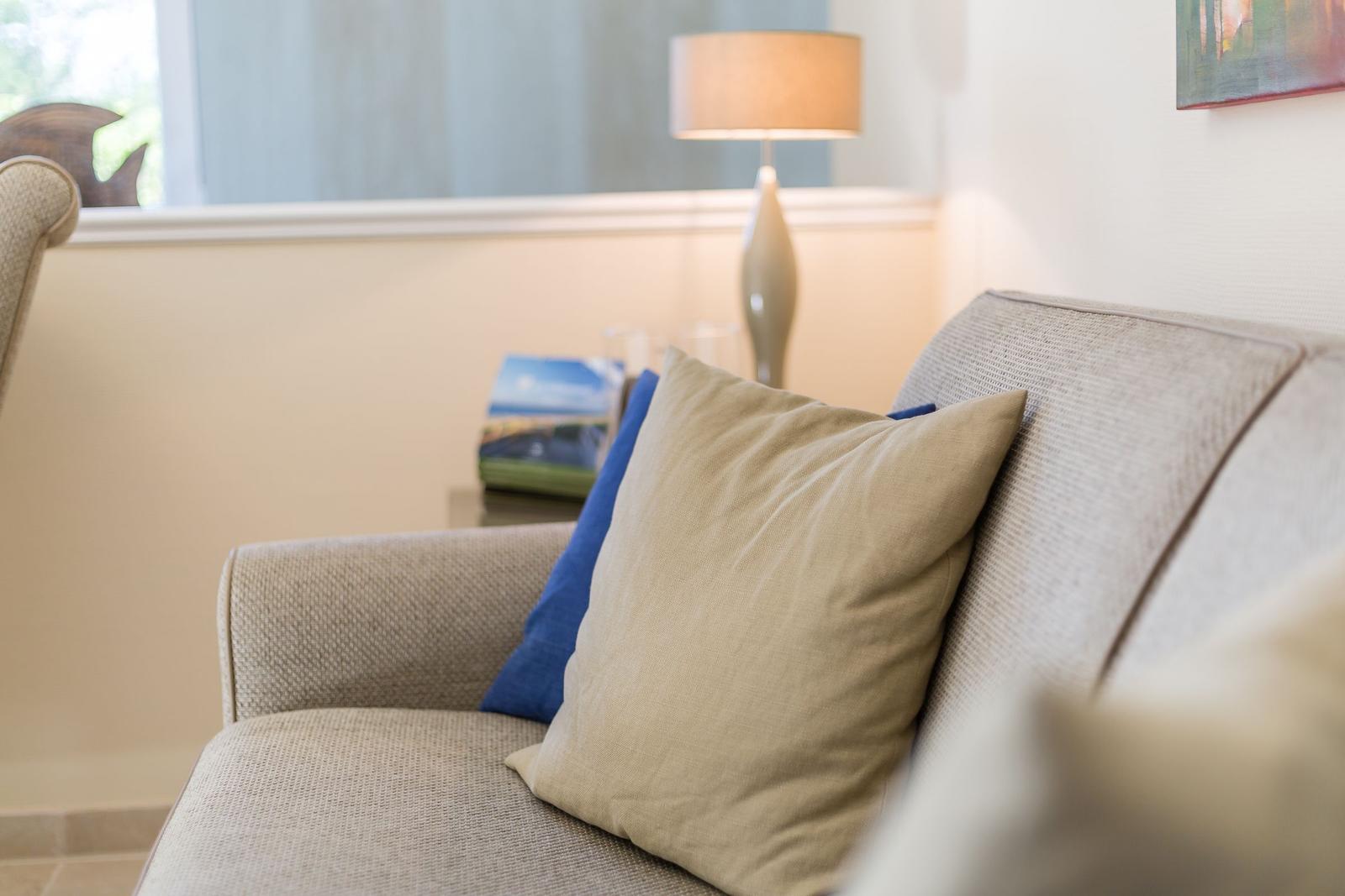 Sofa mit Kissen, Lampe und Bild an der Wand