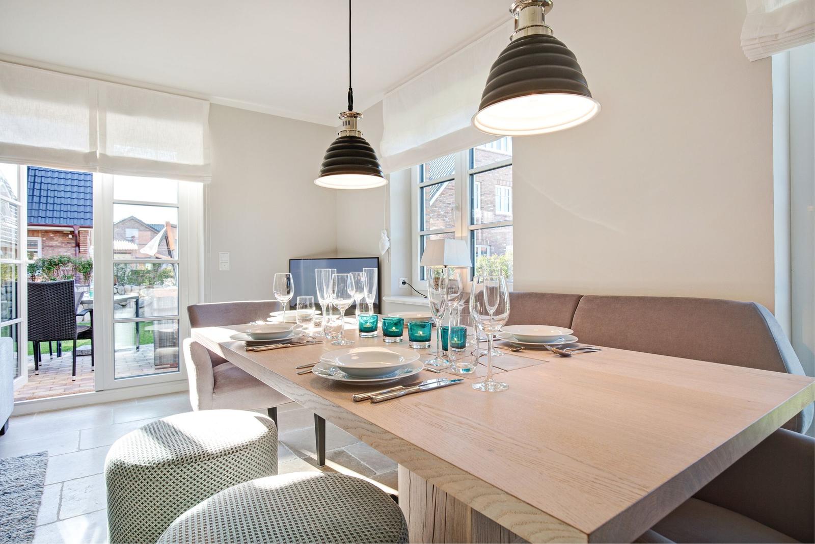 Dining area with wooden table, bench, and pendant lights. Access to terrace with garden furniture.