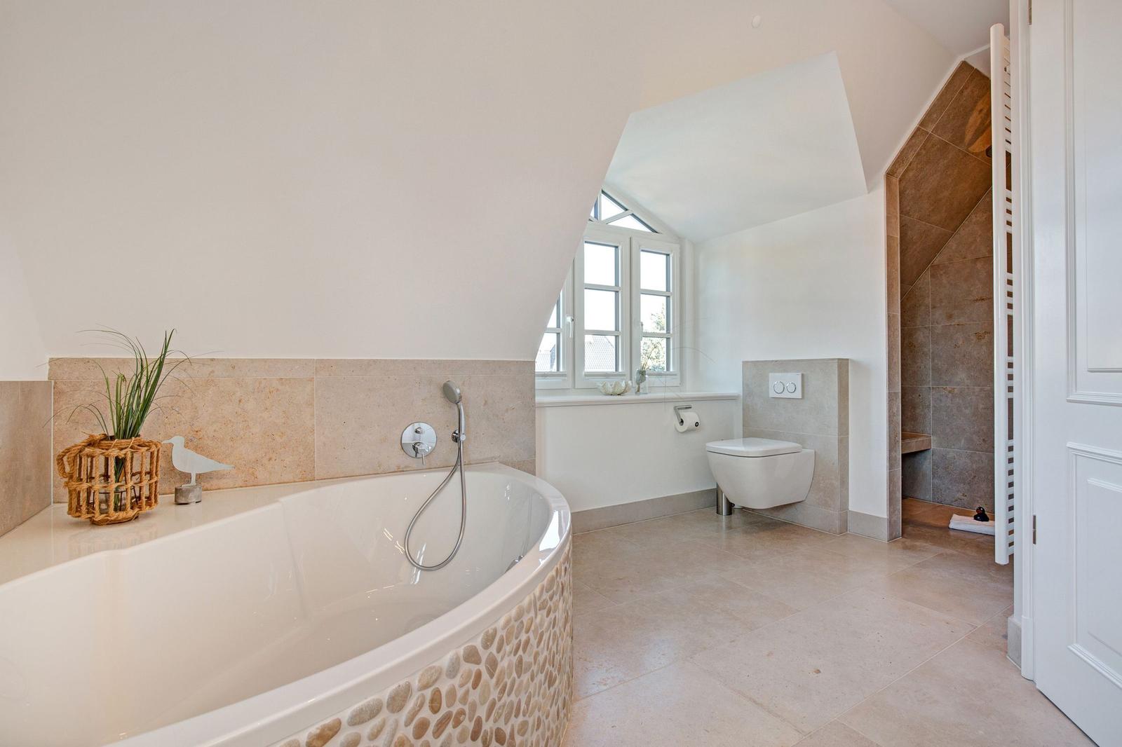 Bathroom with bathtub, toilet, and shower under sloped ceilings.