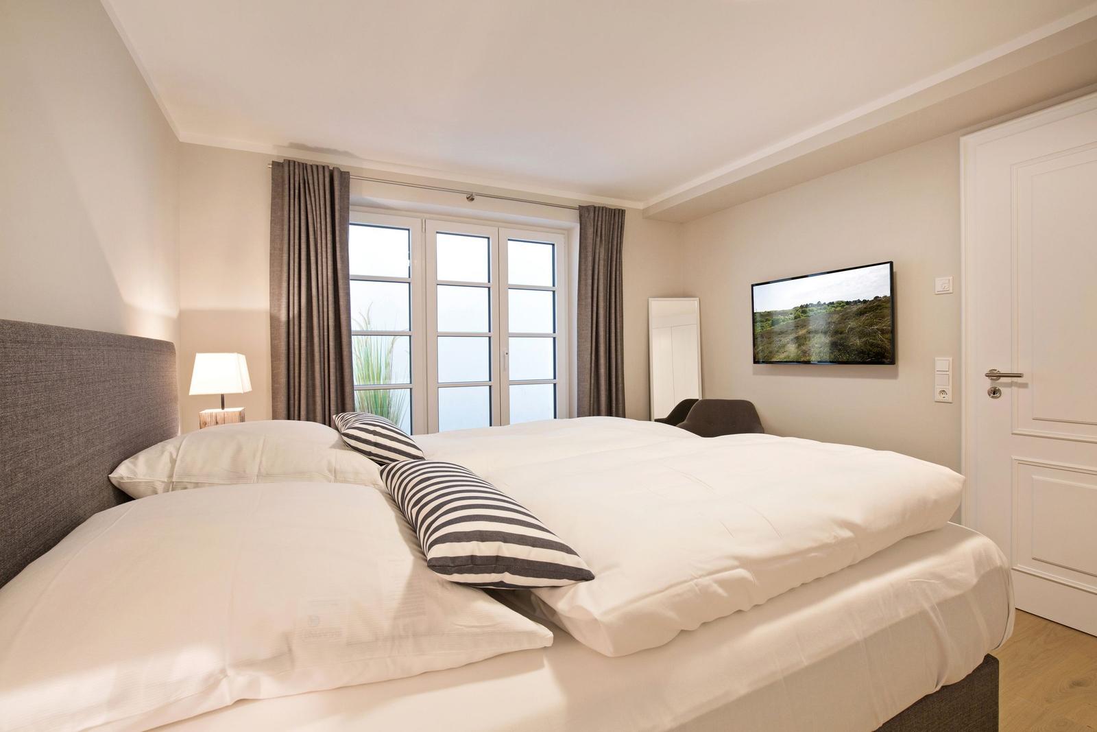 Bedroom with double bed, window, TV, and lamp.
