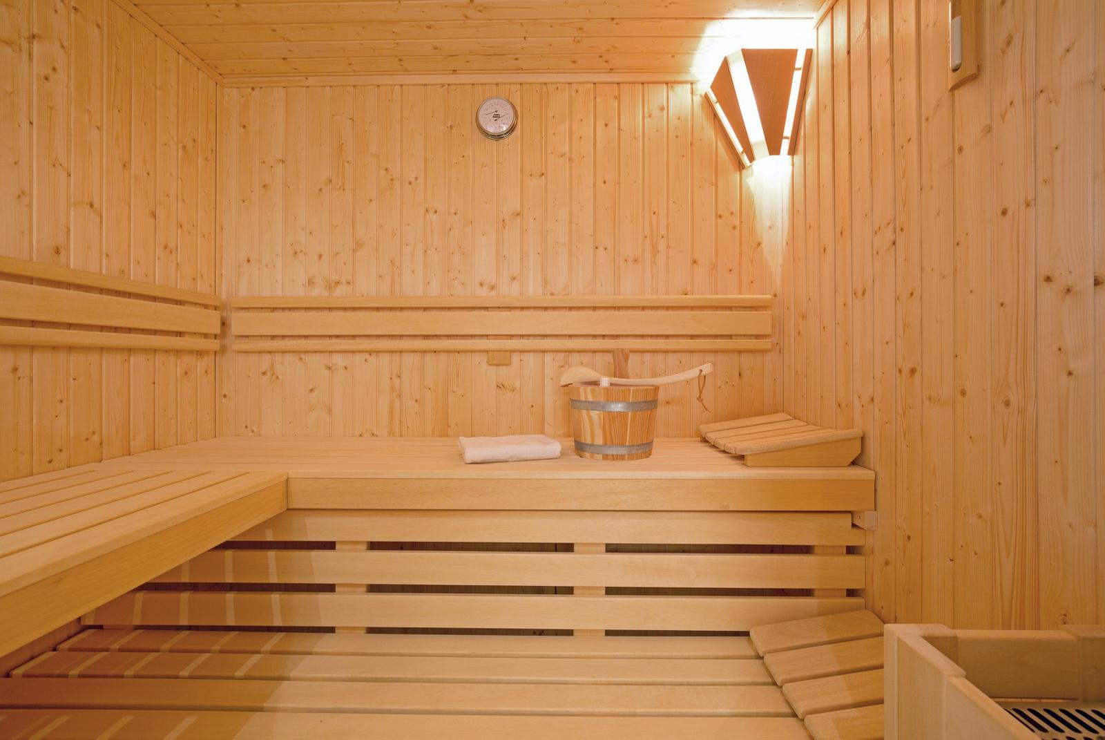 Sauna with wooden bench, bucket, and thermometer.