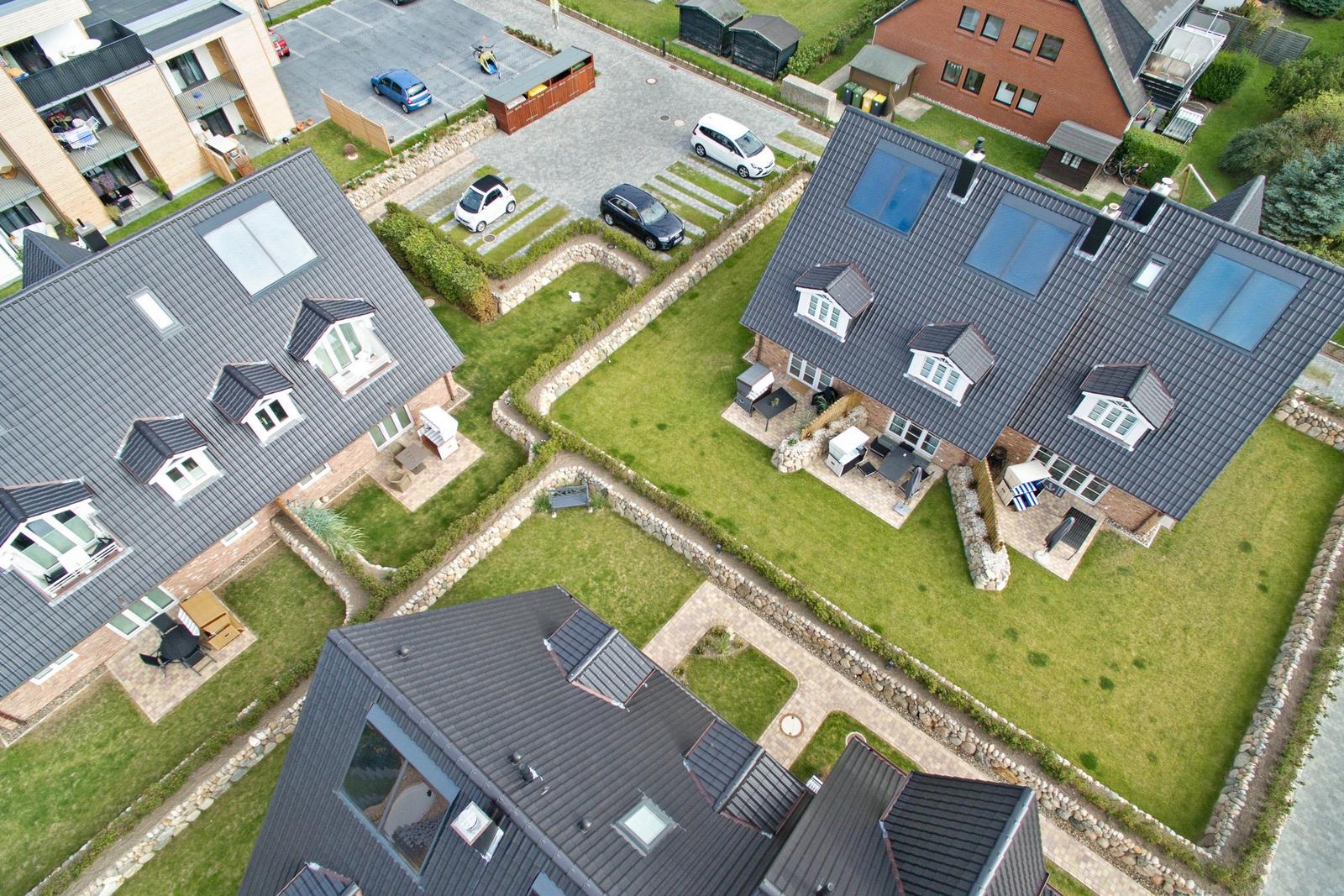 Aerial view of modern houses with gardens and parking areas.