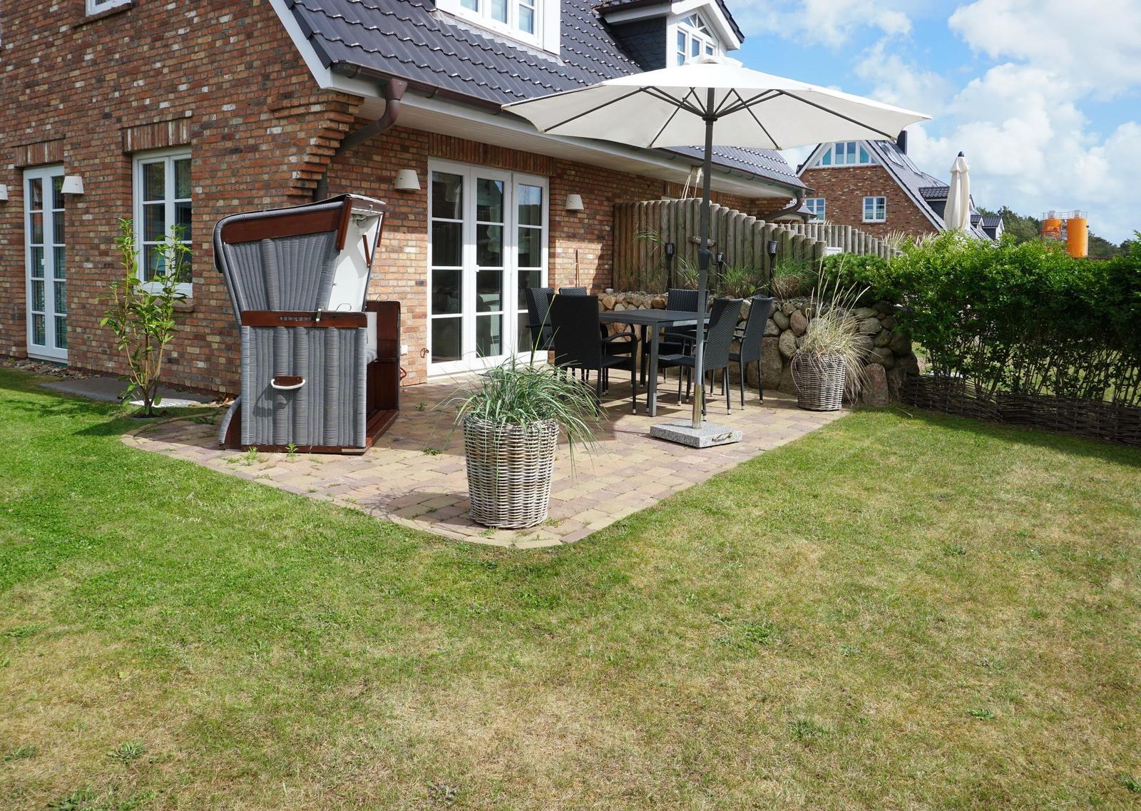 Terrace with table, chairs, and umbrella next to a garden house.