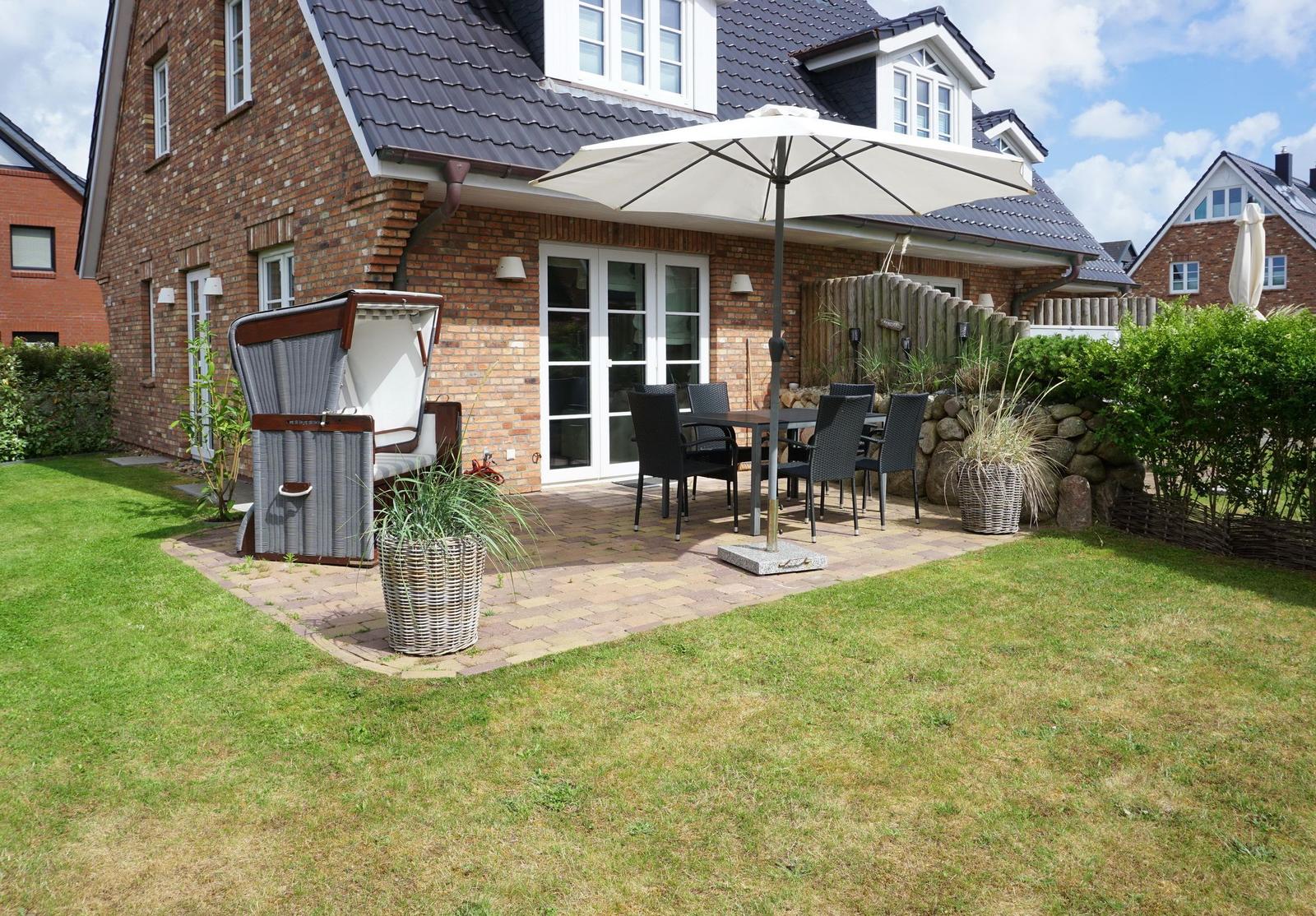 Backyard with terrace, parasol, and garden furniture. Lawn and plants surround the terrace.