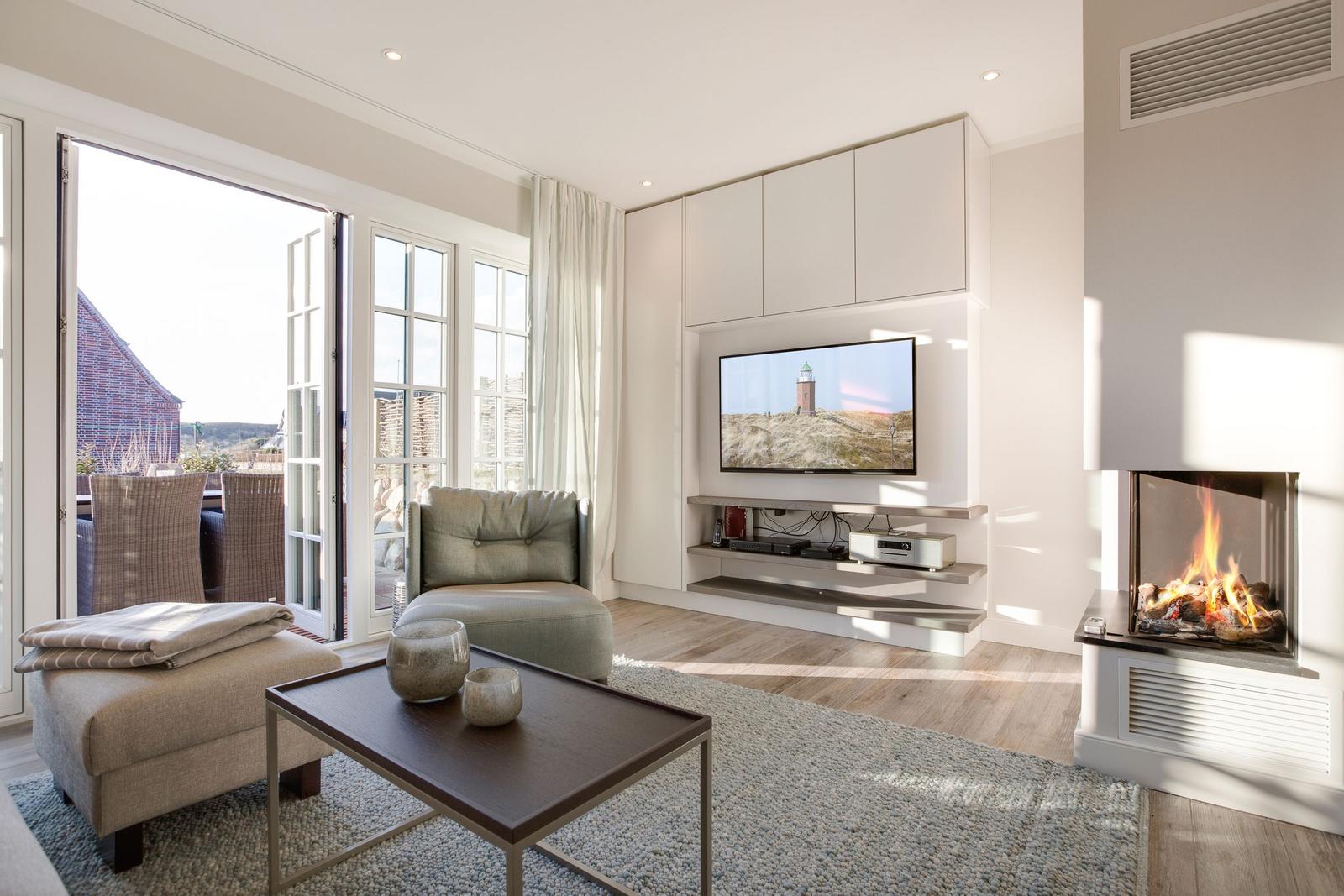 Wohnzimmer mit Kamin, TV und Blick auf Balkon.