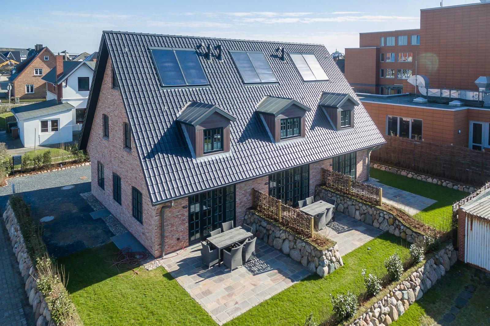 Modernes Haus mit Solaranlage und Gartenbereich mit Terrasse.