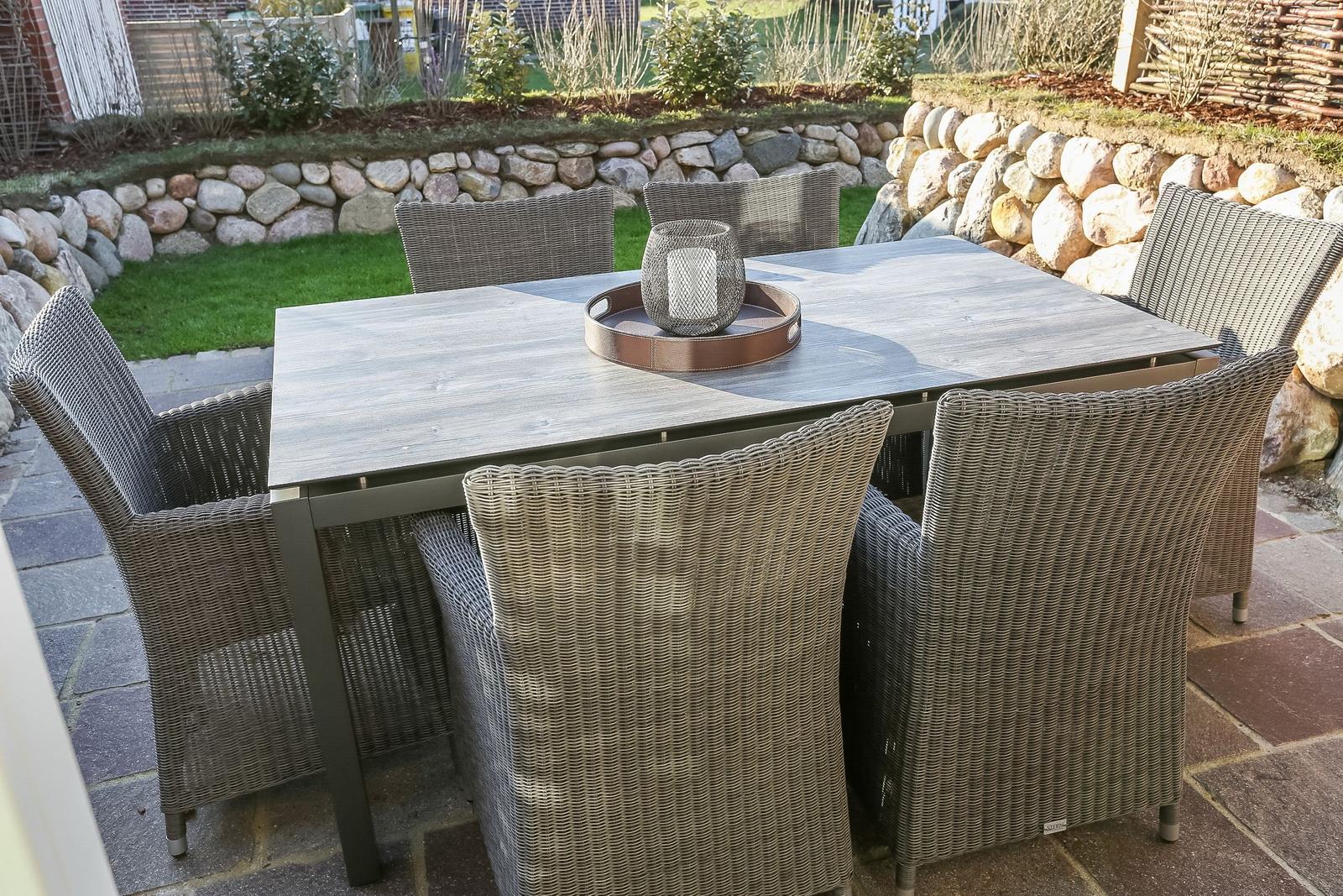Terrassentisch mit sechs Stühlen und dekorativer Laterne auf Steinplatten
