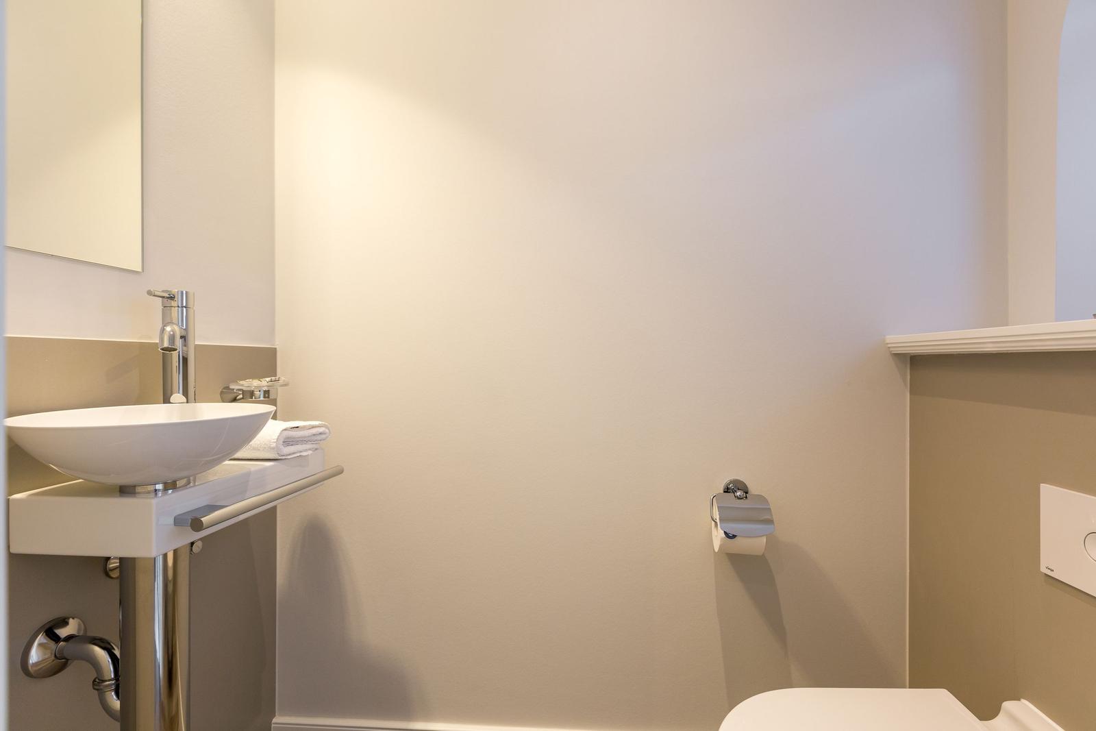 Badezimmer mit Waschbecken, Spiegel und Toilette.