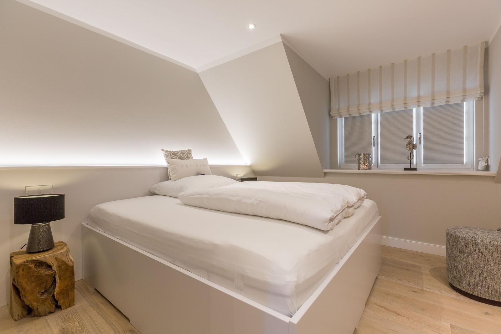 Schlafzimmer mit Doppelbett, Holzboden und Fenster mit Rollladen.