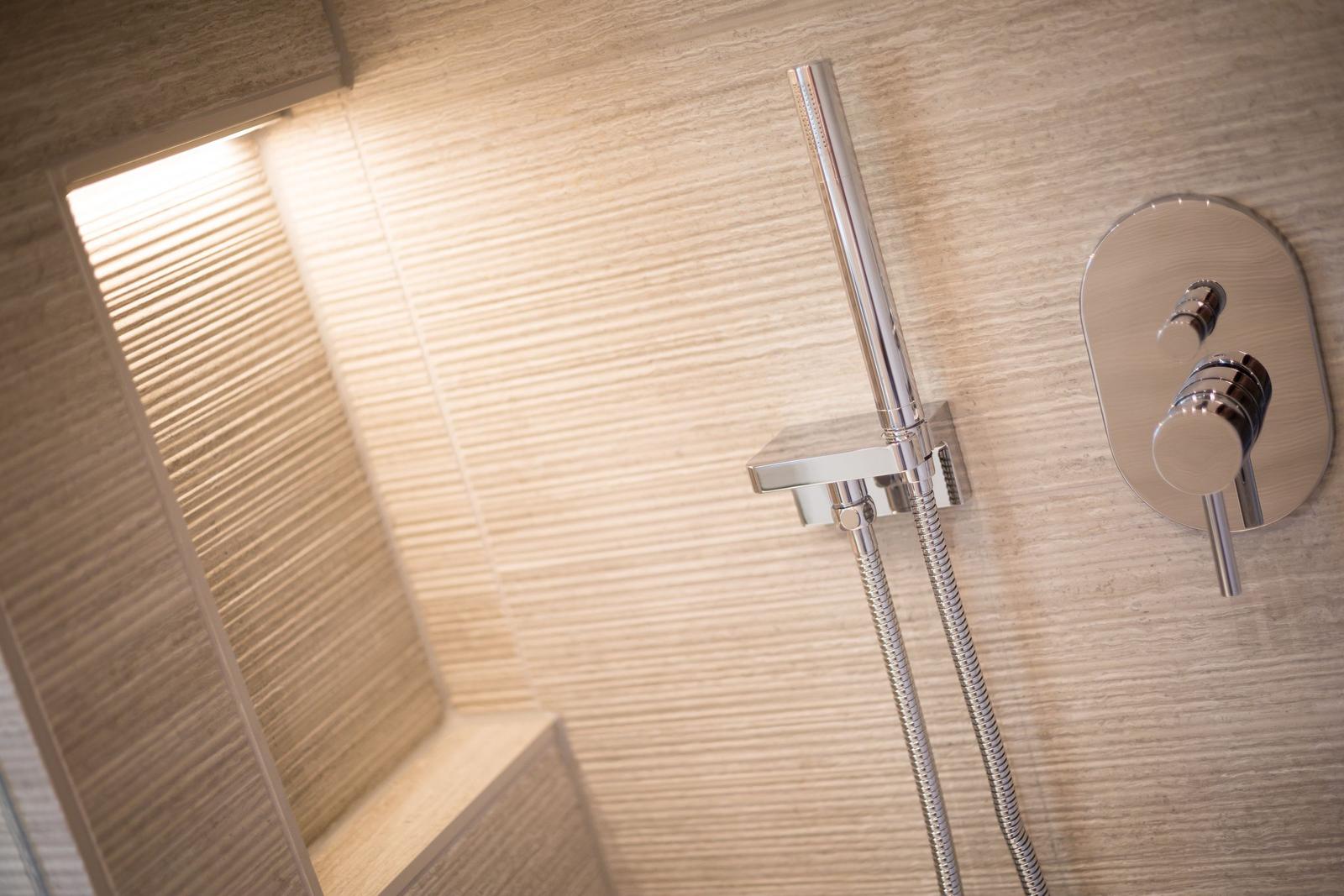 Dusche mit modernem Duschsystem und beleuchtetem Badezimmerbereich.