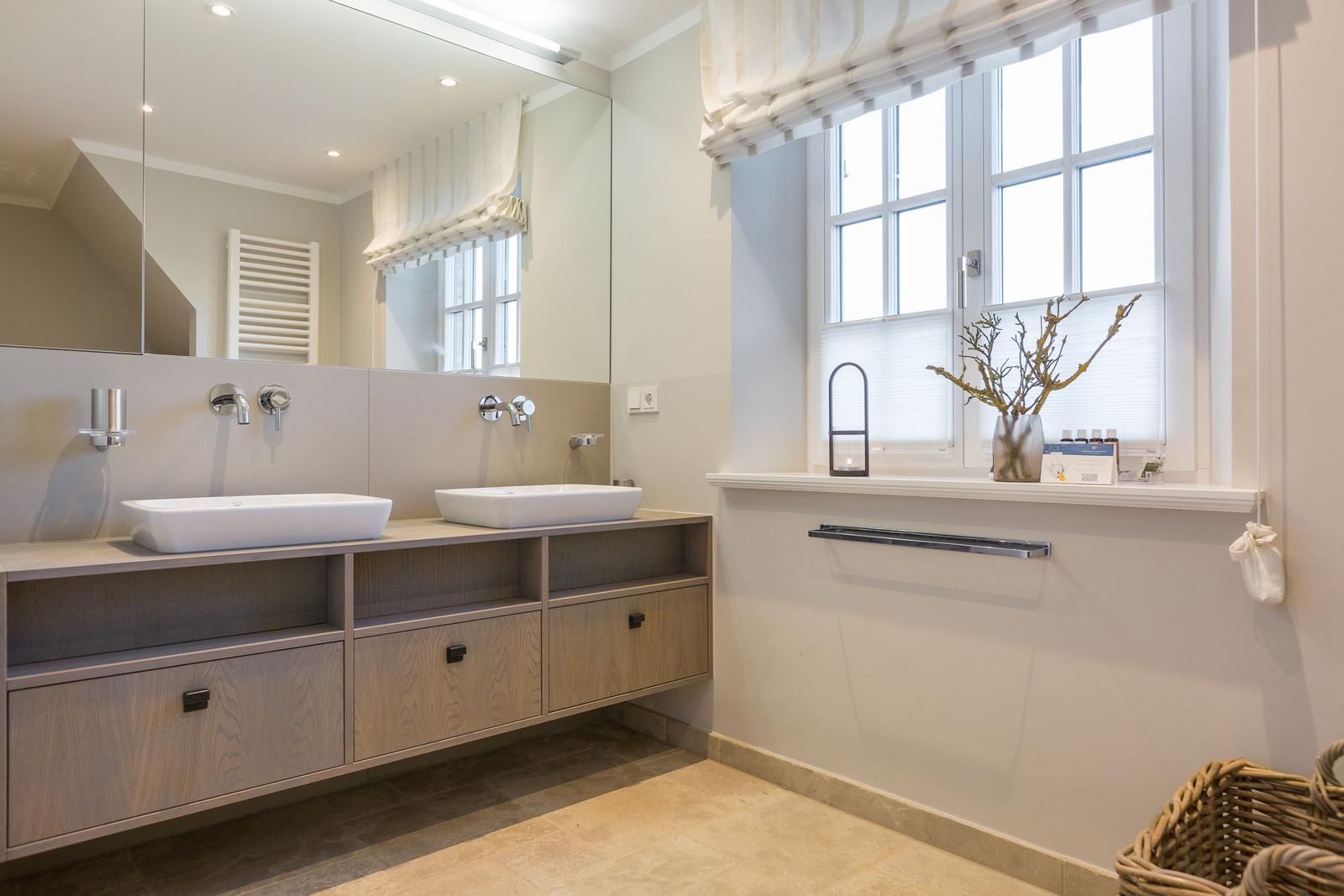 Badezimmer mit zwei Waschbecken, Spiegelschrank und Fenster mit Vorhang.