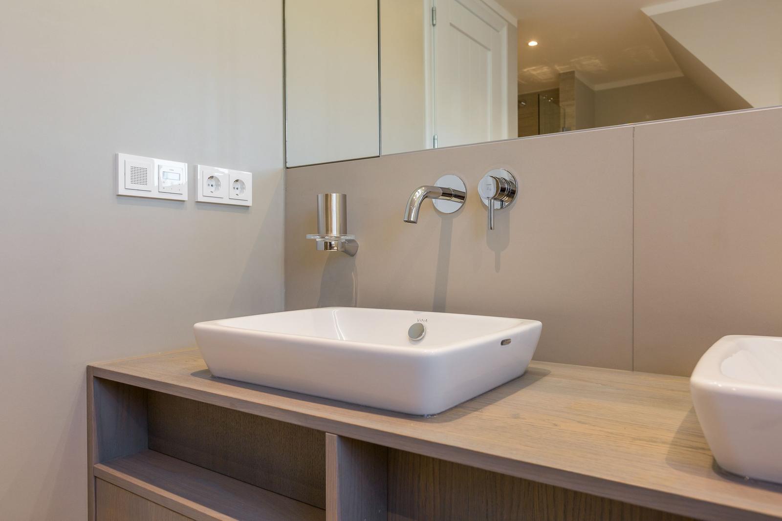 Waschbecken mit Spiegel und Wasserhähnen auf Holzkonsole
