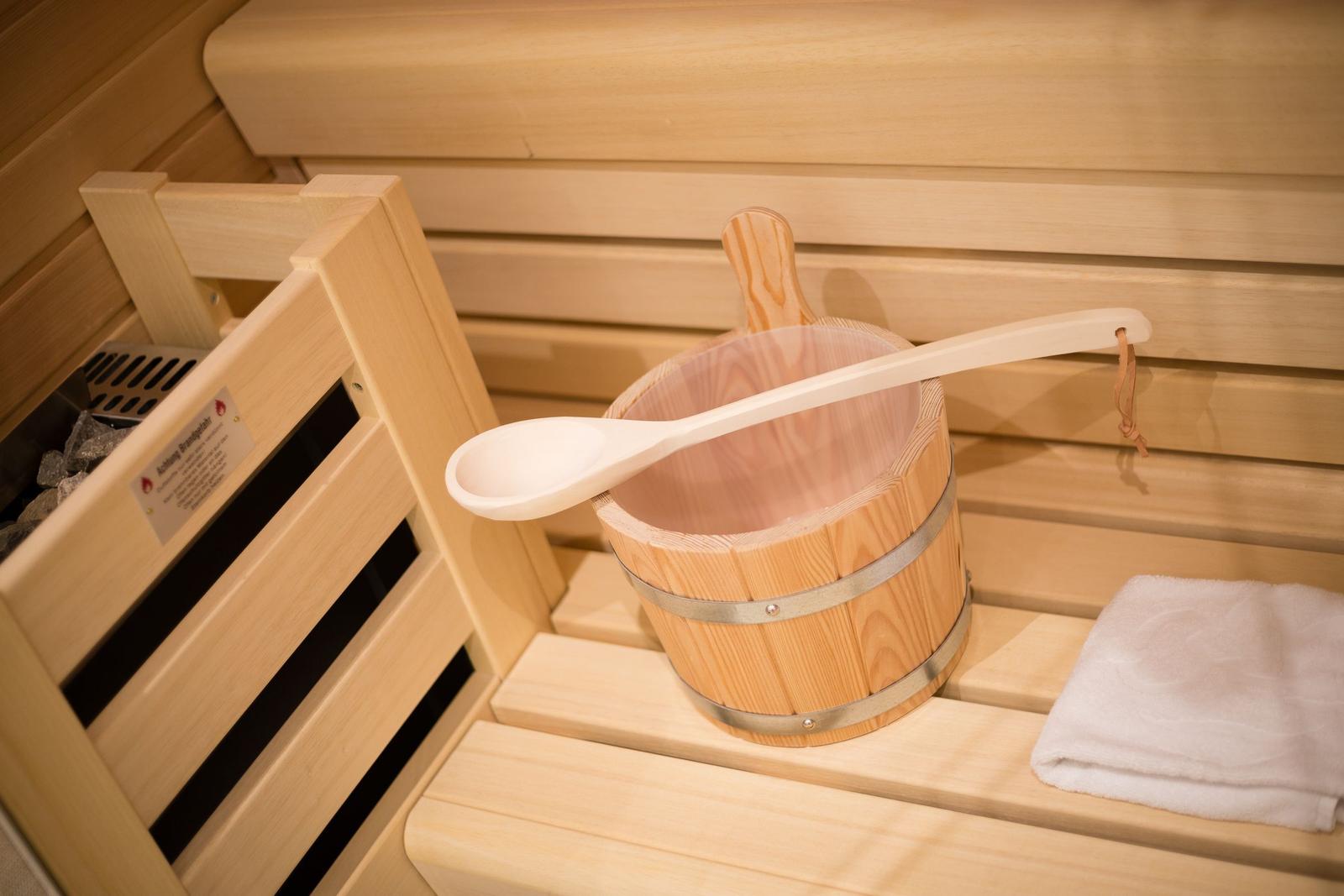 Sauna mit Holztonne, Löffel und Handtuch auf Bänken