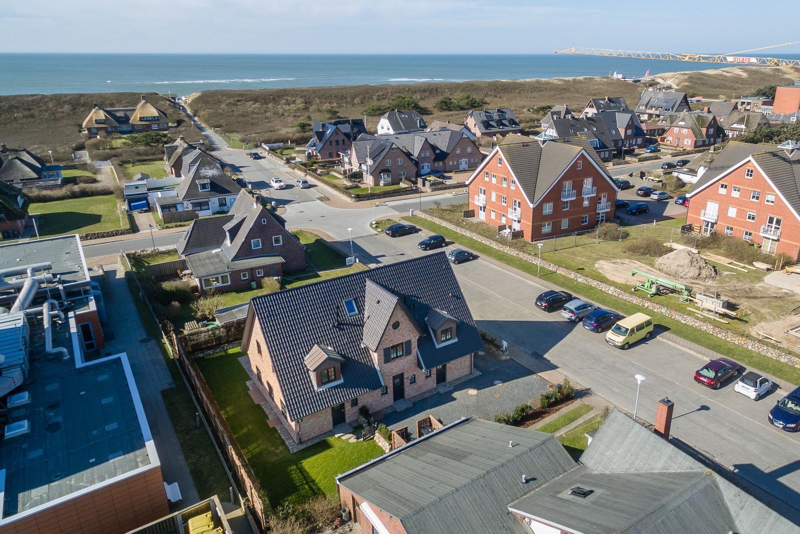 Aerial view of coastal village with houses, roads, and ocean in background.