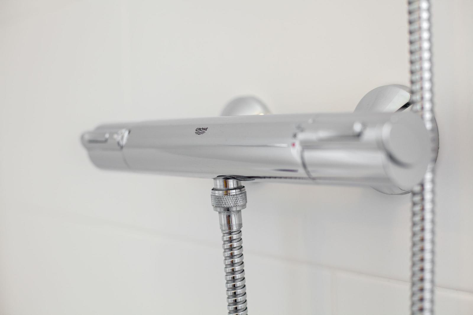 Shower area with chrome shower system and flexible hose connection.