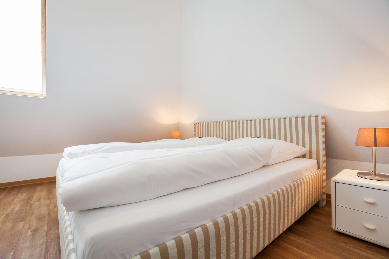 Bedroom with bed, nightstand, and lamp.